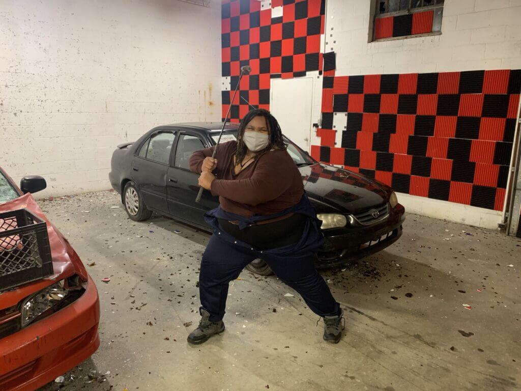 woman in a coverall wielding a bat like a weapon